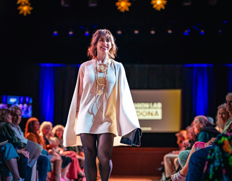 A Sensational Sedonan in a white cape walking the Fashion Lab runway